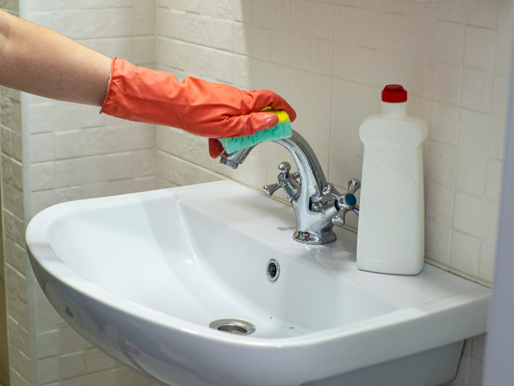 person-hand-holding-mint-sponge-cleaning-bathroom-sink-faucet