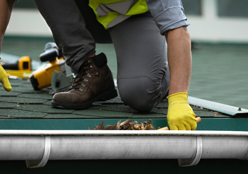 man-worker-is-cleaning-clogged-roof-gutter-from-dirt