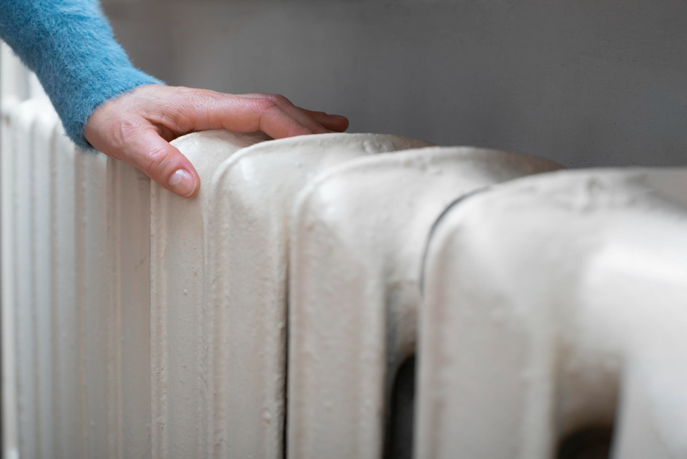 caucasian-female-warming-up-hands-near-hot-water-radiator-space-text