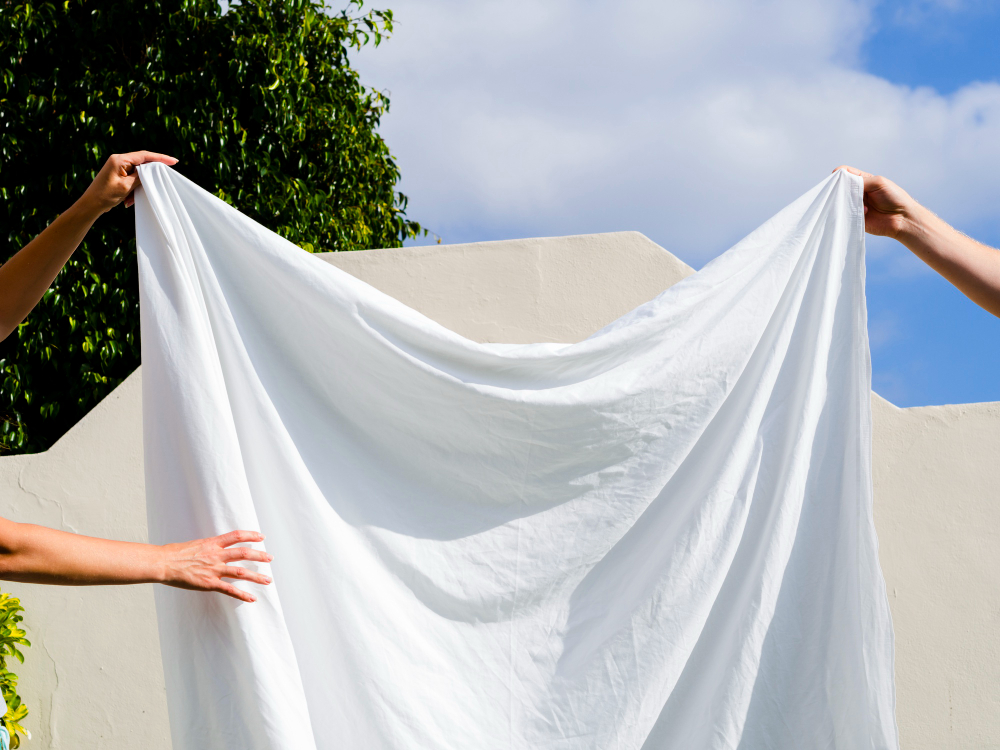 Close Up Two People Hanging White Sheet Line