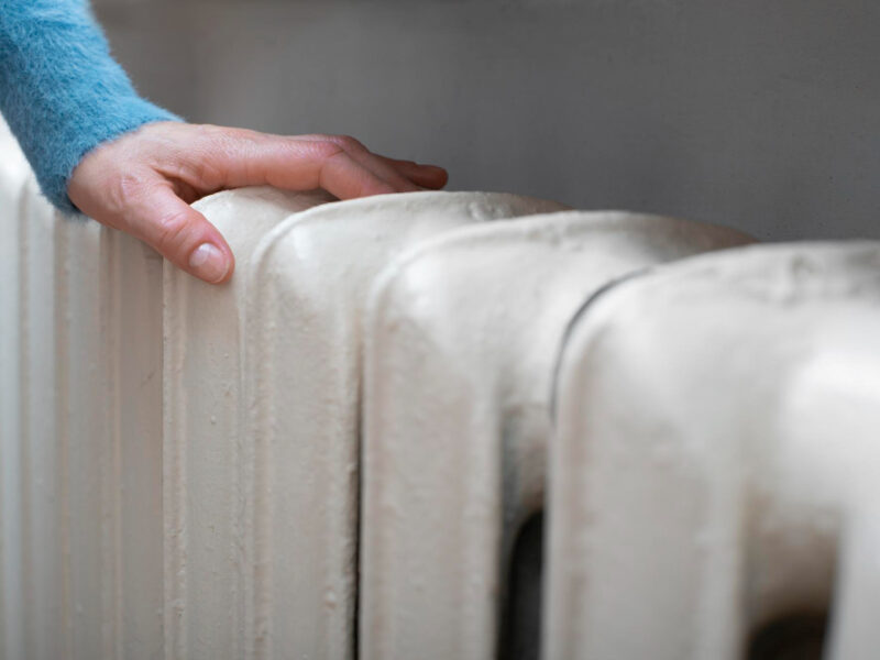 Caucasian Female Warming Up Hands Near Hot Water Radiator Space Text