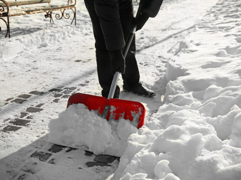 Man Removing Snow With Red Shovel