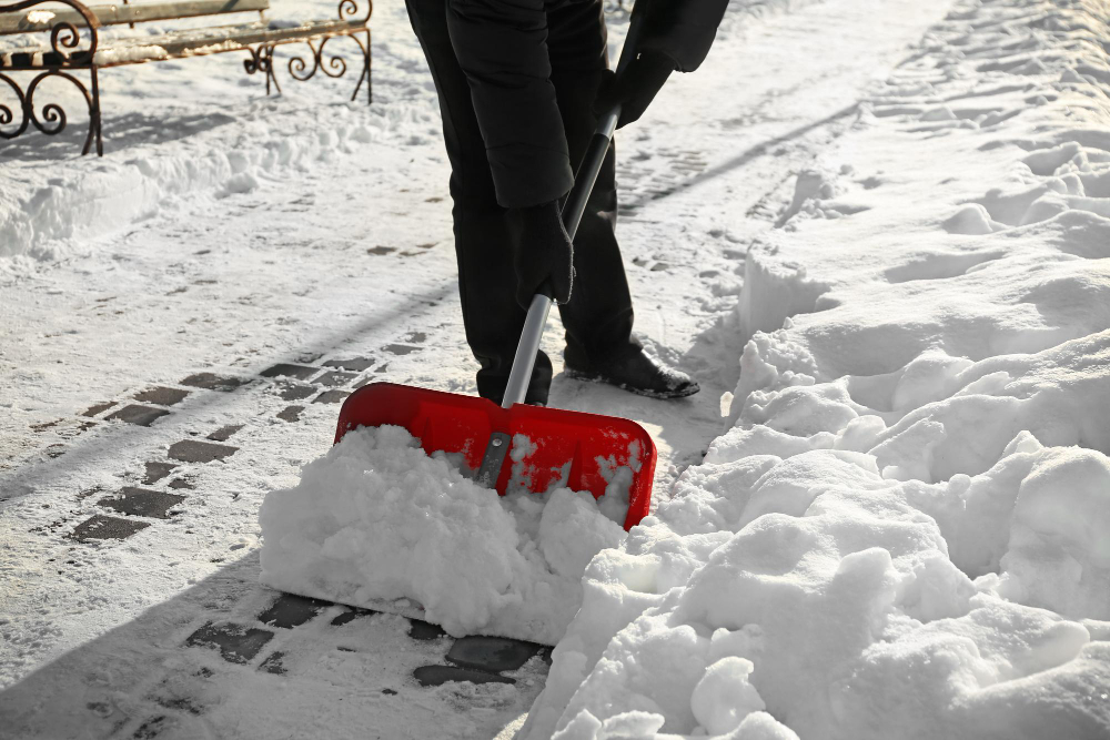 Man Removing Snow With Red Shovel