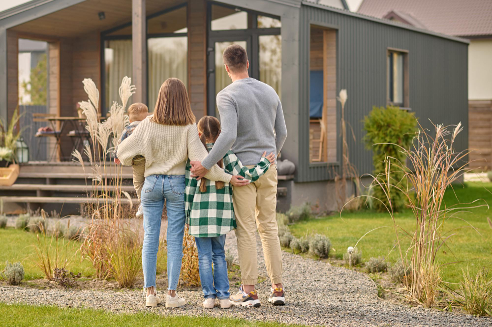 Back View Family Hugging Admiring Their Home